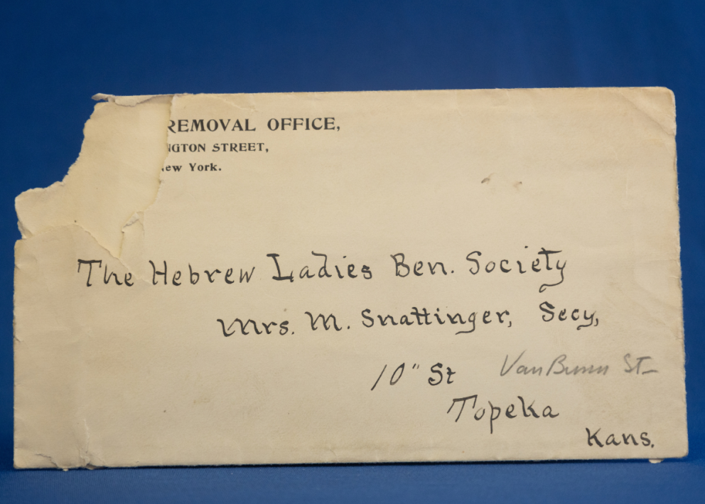 Torn cream envelope with Topeka address